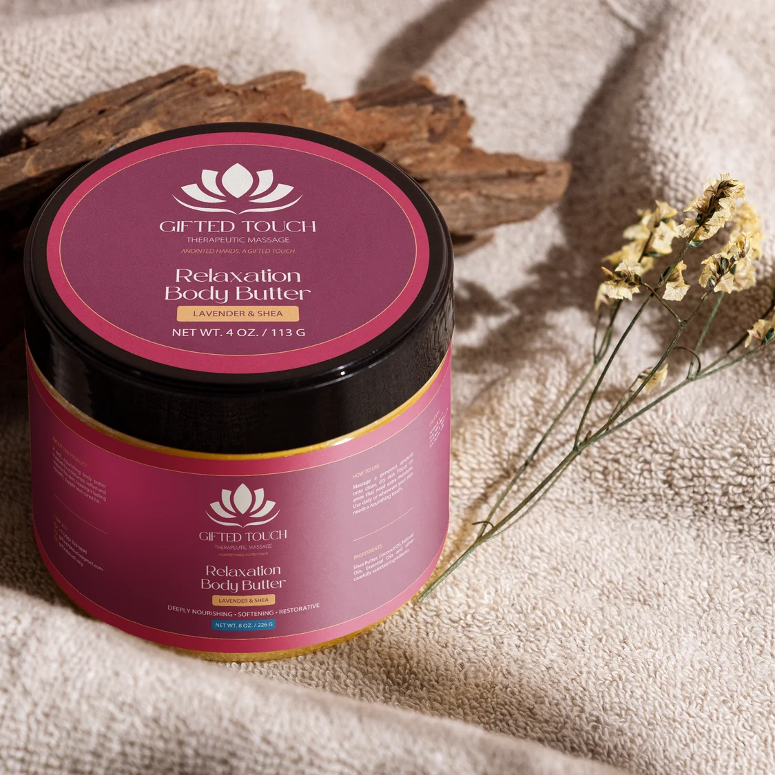 Relaxation Body Butter jar in its new Gifted Touch label, on a towel beside dried flowers